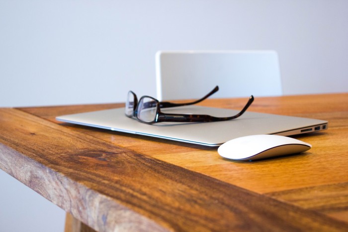 Glasses on Macbook next to mouse