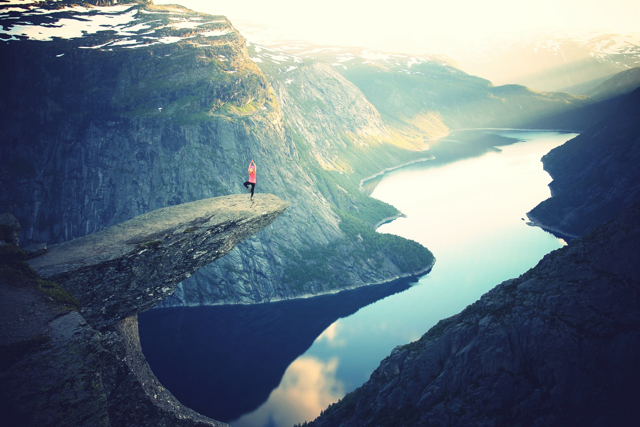 Woman doing yoga pose on cliff overlooking river